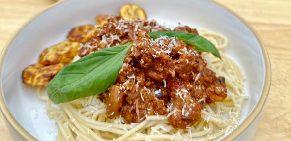 Jollof spaghetti bolognese served on a plate with garnish