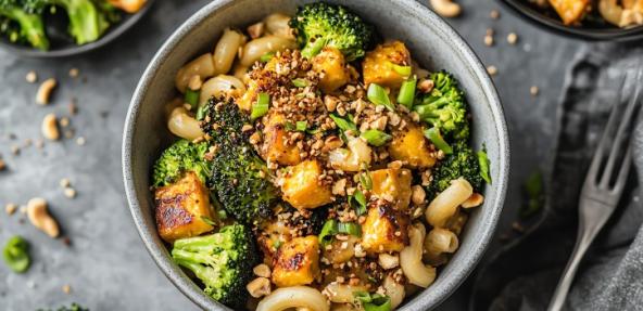 Vegetable pasta bowl with nuts and spring onions sprinkled on top