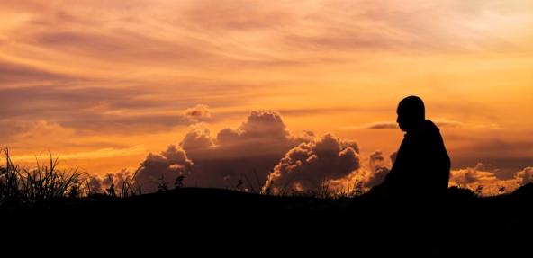 Buddhist monk meditating during sunset