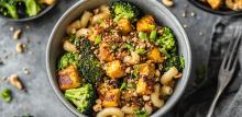 Vegetable pasta bowl with nuts and spring onions sprinkled on top