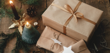 Presents wrapped in brown paper with a festive background surrounded by pine cones and Christmas tree candles