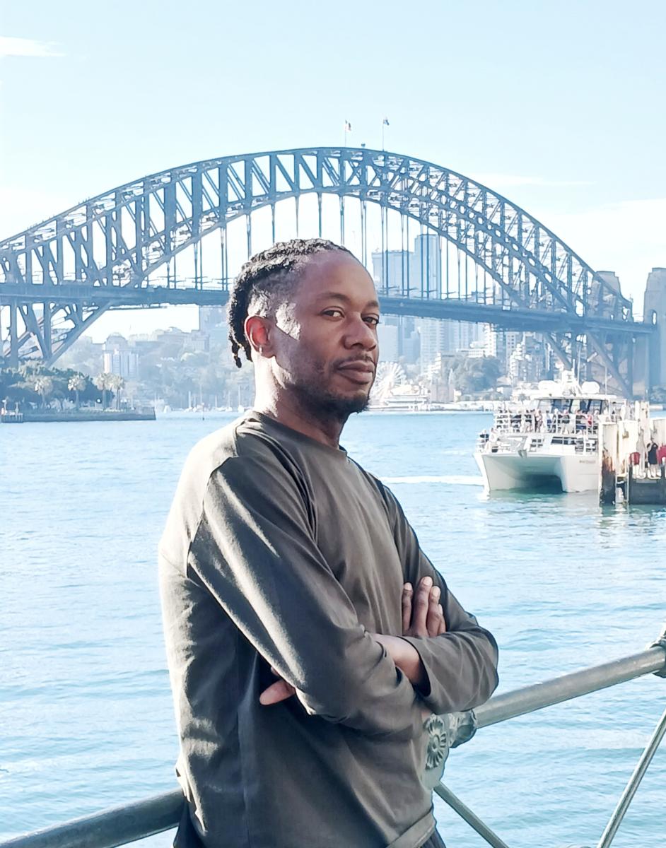 Portrait of Akil Goin against a background of a bridge.