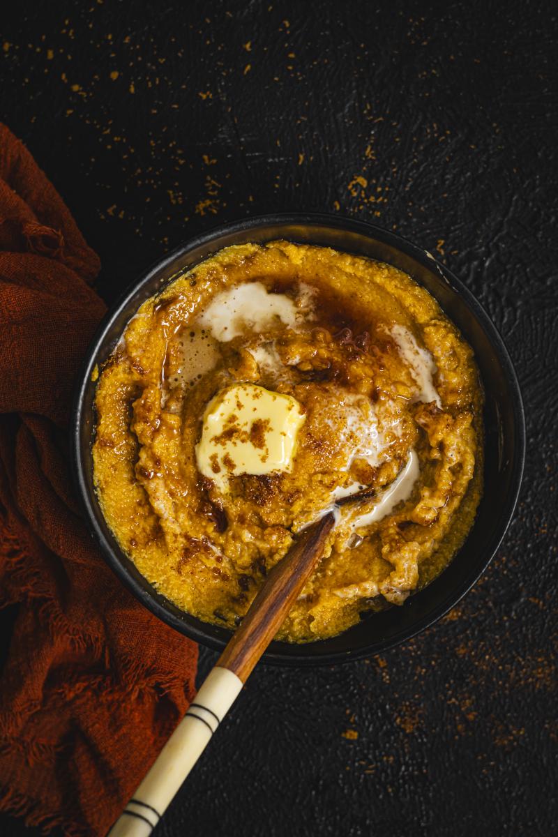 This is a picture of a bowl of butternut cornmeal porridge, against a dark background. 