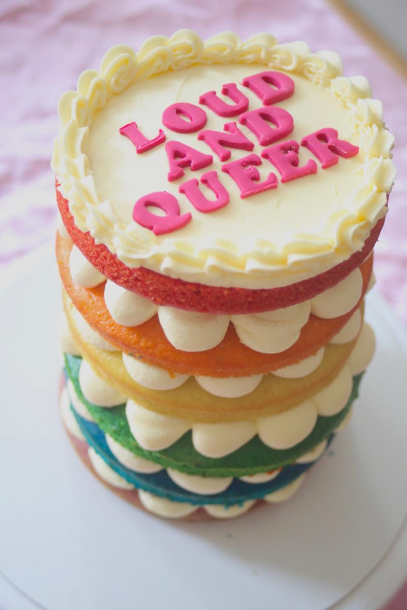 Vegan rainbow cake with 'loud and queer' icing on the front