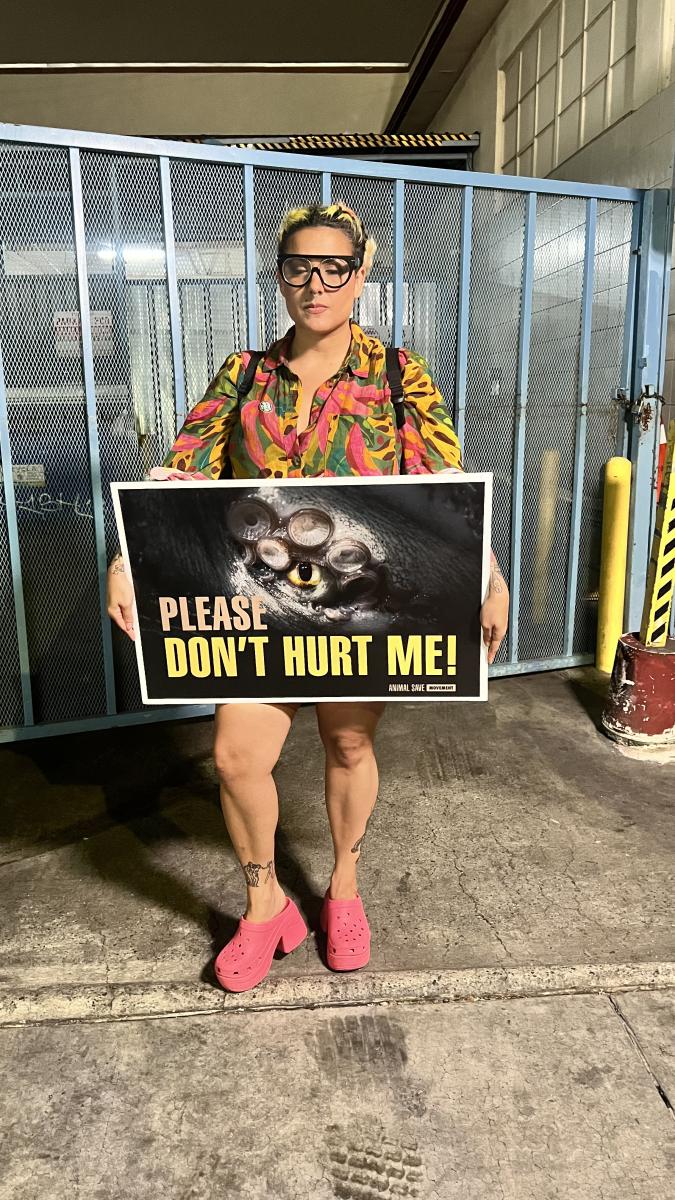 Vegan LGBTQIA+ influencer Nati Casanova standing with an Animal Save Movement banner