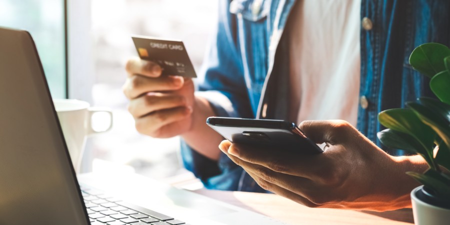 Person holding credit card completing checkout for online shopping on laptop