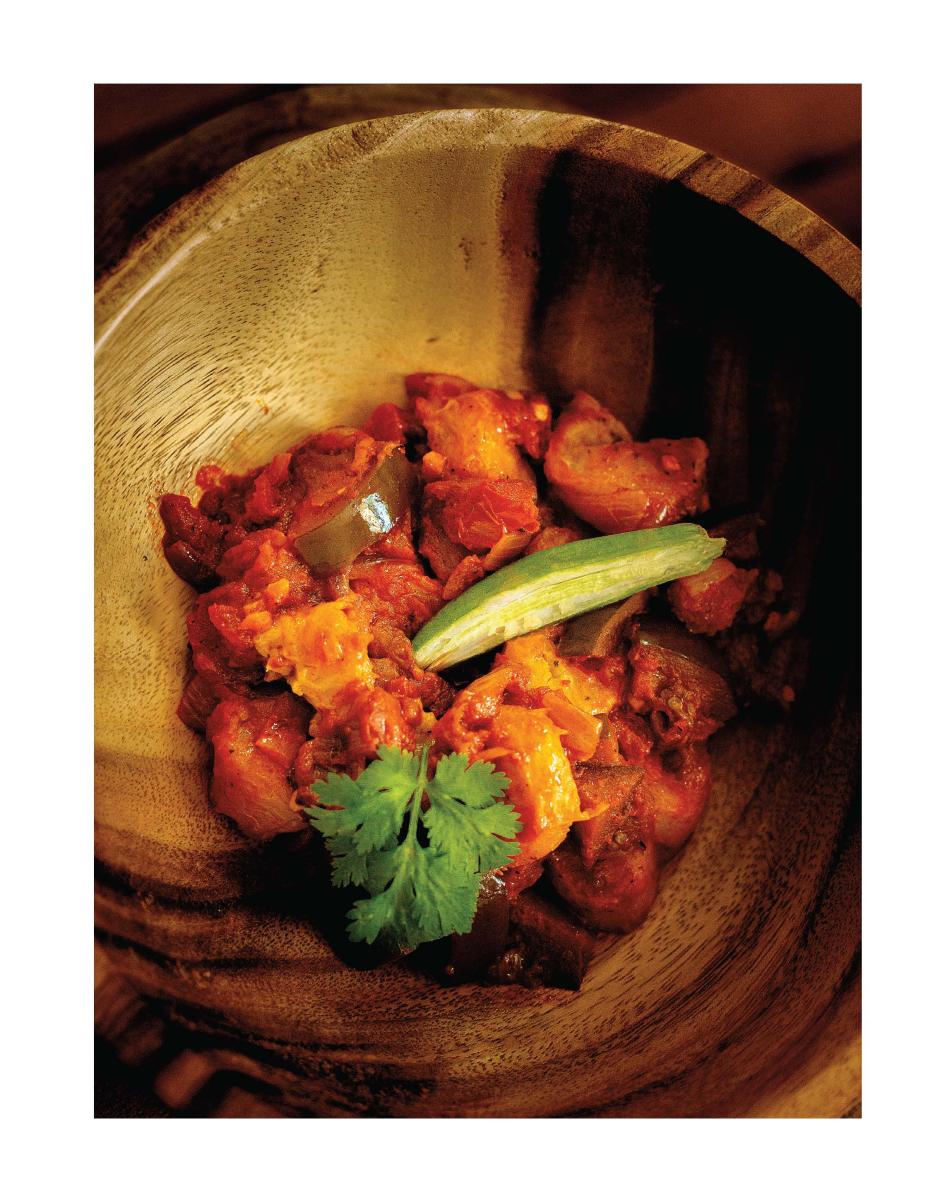 Plantain and eggplant stew, served in a wooden bowl with a garnish of corriander and green chili