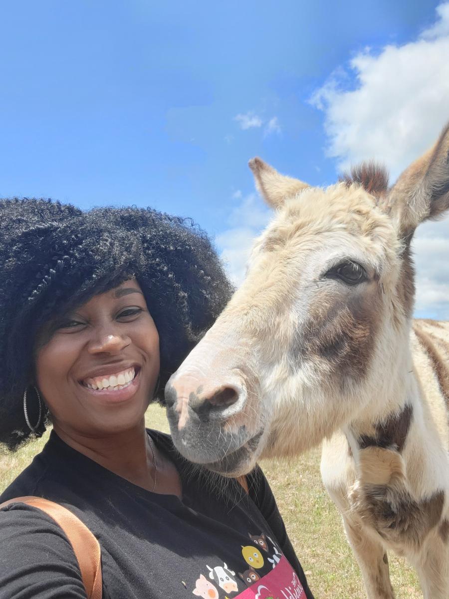 Tabatha James at an animal sanctuary with a donkey